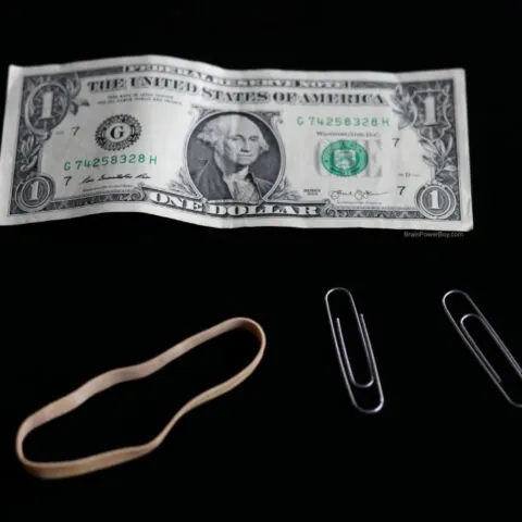 One dollar bill with paperclips and rubber band for trick
