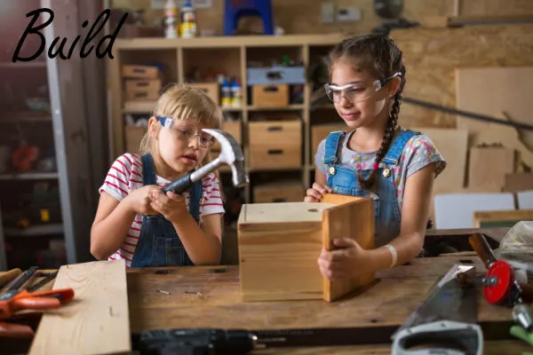 Two girls building a birdhouse together as a family activity
