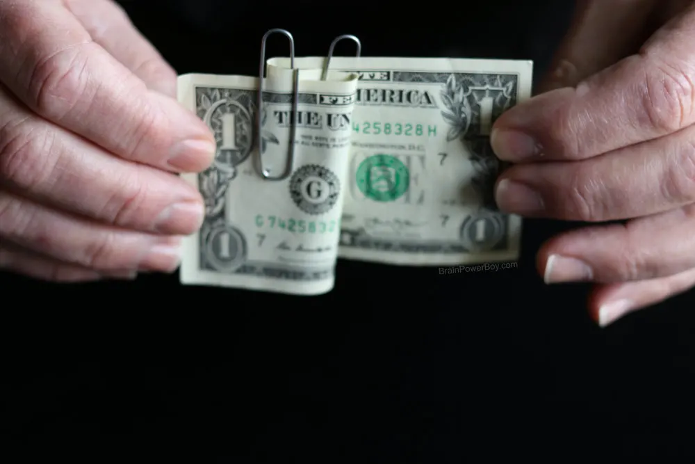 two paperclips attached to dollar bill